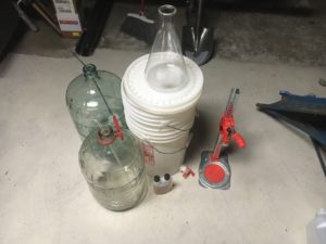 two carboys, two buckets, a flask, and a bottle capper